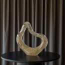 a striking decorative sculpture designed to elevate contemporary interiors. Featuring a smooth flowing silhouette and a transparent glass body filled with delicate gold accents, this artistic piece brings sophistication and visual interest to any room.